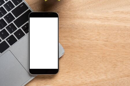 smartphone with blank screen is on top of notebook over wood office desk table. Top view with copy space, flat lay.の写真素材