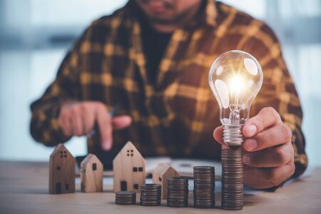 businessman holding lightbulb and use calculator . concept saving money and finance accounting for the future.idea innovation.の写真素材