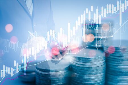 Double exposure of success businessman using digital tablet with rows of coins for financial stock market graph and rows of coins growth,business investment and currency exchange background,の写真素材