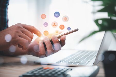 Social media interactions on mobile phone, concept with notification icons of like, message, email, comment and star above smartphone screen, person hands holding device, internet digital marketingの写真素材