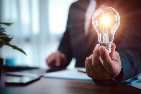 businessman hand holding light bulb with finance document and tool,concept of New ideas for business and fonance.の写真素材