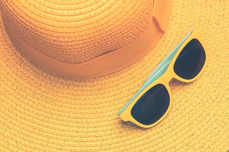 beach accessories on yellow background. sunglasses, and yellow striped hat. summer is coming conceptの写真素材