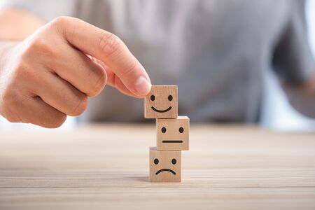 Hand of a businessman chooses a smiley face on wood block cube, The best excellent business services rating customer experience, Satisfaction survey conceptの写真素材