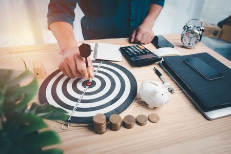 hand man with a dart in his hand pinning on the target board. target for saving and financial planning concept.の写真素材