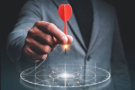 Businessman holding red darts with virtual screen dart board .targeting the business conceptの写真素材