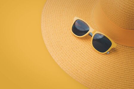 beach accessories on yellow background. sunglasses, and yellow striped hat. summer is coming conceptの写真素材