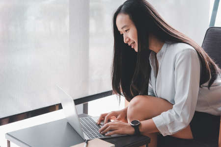 beautiful asian woman using computer laptop in coffee shop and she's smiling face.with copy space for text or design and Advertisement.の写真素材