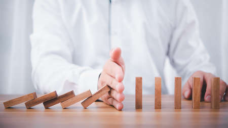 Businessman hand stop falling down of wood block .planing and strategy business disruption concept.の写真素材