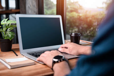 Mockup image of a man using laptop with blank screen on wooden table.concept work form home, stay at home.の写真素材