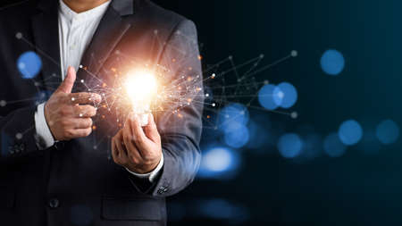 Hand of man holding illuminated light bulb, idea, innovation and inspiration concept.concept creativity with bulbs that shine glitter.の写真素材