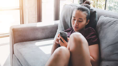 beautiful asian woman using smartphone on the sofa relaxing corner in her home.stay at home concept.の写真素材