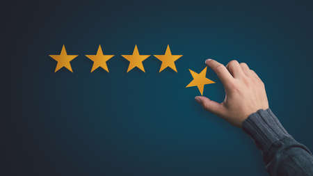 Customer satisfaction concept. hand put the stars to complete five stars. with copy space.giving a five star rating. Service rating, satisfaction concept.の写真素材
