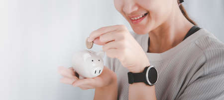 Woman's hand putting coins in piggy bank.saving money concept.for banner, web page or cover templateの写真素材
