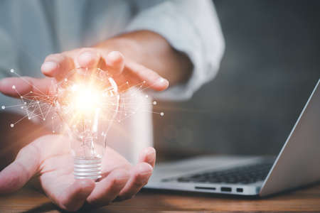 Businessman showing a bright light bulb in his hand, Success is achieved through creativity,...