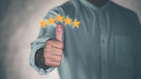 Customer service satisfaction survey concept.Business people or customers are thumbs up to show their satisfaction in service.Men give a 5 star satisfaction rating.の写真素材