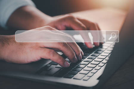 Searching Browsing Internet Data Information with blank search bar.Search Engine Optimization SEO Networking Concept.hand of businessman working with computer laptop on desk in office.の写真素材