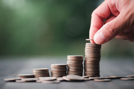 business finance and saving money investment concept, Hand with Money coin stack growing graph saving concept. Balance savings and investment.の写真素材