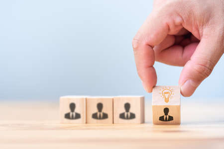 Leader with idea and innovation. hand is choosing Wood block with human symbol and light bulb icon standing out from the crowd. Successful business.の写真素材