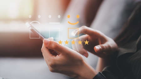 Customer service satisfaction survey concept.Business people or customers show satisfaction through the application on the phone screen. By giving the most satisfaction rating and 5 stars.の写真素材