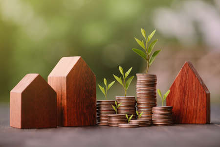 Investment in the real estate business. Money coin stack growing graph and wood house model. Loans for the purchase of residential houses.Save for the future.の写真素材