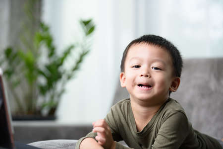Asian boy with a cute face and good temper is looking and smiling at the camera.の写真素材
