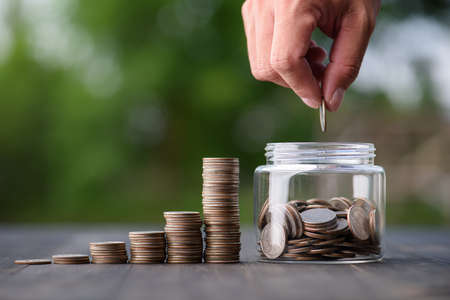 business finance and saving money investment , Money coin stack growing graph with hand putting coin on piggy bank saving concept. Balance savings and investment.の写真素材