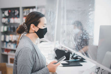 Young asian woman wearing surgical mask in shopping mall. New normal and lifestyle concept with COVID-2019.の写真素材
