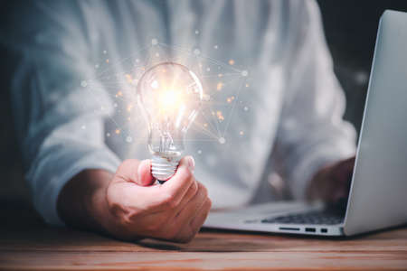 hand of a man with a light bulb with network connection line And he is using a notebook computer. The idea of ââinspiration from online technology.innovation idea concept.の写真素材