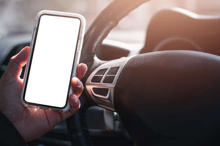 man's hand is holding a smartphone with a blank white screen while driving. The concept of a mobile...