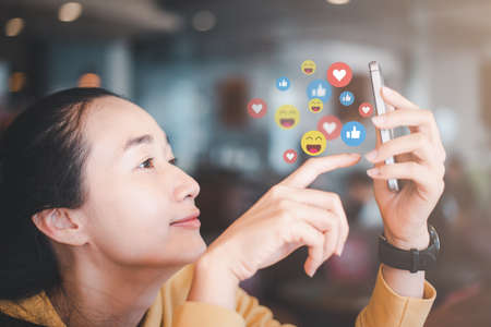Social media and digital online concept, woman using smart phone in coffee shop. The concept of living on vacation and playing social media.の写真素材
