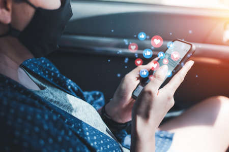 Social media and online digital concepts, women wearing a mask, using a smartphone on a car The concept of life during the outbreak of the Covid-19 virus And playing social mediaの写真素材