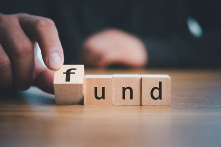 Business finance and investment concept. Hand of business man flips one revealing an Text fund on wood cube block. Fund Purchasing Concept.の写真素材