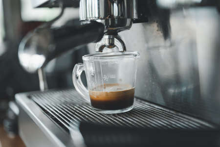 Espresso coffee pouring from espresso machine. Barista details in cafeの写真素材