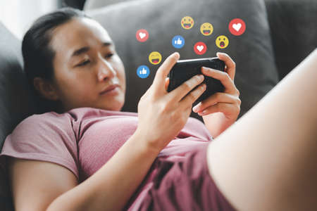 Social media and digital online concept, woman using smart phone on sofa at home. The concept of...