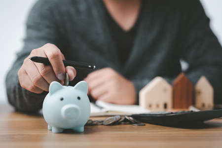 business people working at desk with piggy bank box.business finance saving and investment concept. hand put money coin into piggy bank for saving money wealth.の写真素材