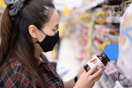 Shopping in the supermarket. Asia Woman checking food labelling.Read product information.の写真素材