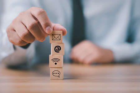 Businessman hand putting wooden block cube with icon Chat, email, address, wifi . Website page...