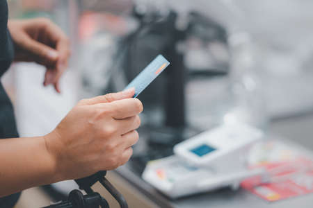 Woman at the supermarket checkout, she is paying using a credit card, shopping and retail conceptの写真素材