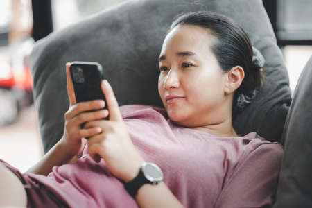 Beautiful asian girl Is using a smartphone And she is smiling in satisfaction.の写真素材