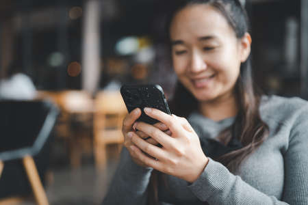 Beautiful asian girl Is using a smartphone And she is smiling in satisfaction.の写真素材
