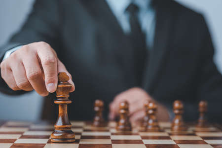 Businessman moving chess piece on chess board game concept for ideas and competition and strategy, business success concept, business competition planing teamwork strategic concept.の写真素材