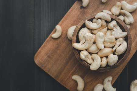 raw cashew nuts in wooden bowl on rustic table, healthy vegetarian snackの写真素材