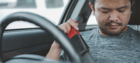 Portrait of smiling Asian man fastening seat belt in the car. safety concept. front view in car.