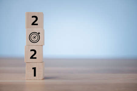 wood cubes with New year 2021 and goal or target icon. concept of New year Business goals and...