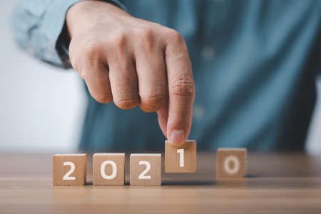 male hand hand putting wood cube for 2021 years. creative background for the new year. happy new years 2021 conceptの写真素材
