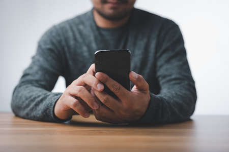 Young casual Businessman holding and using smartphone for sms messages, man typing touchscreen cell phone in the office. business, lifestyle, technology and Social media network conceptの写真素材