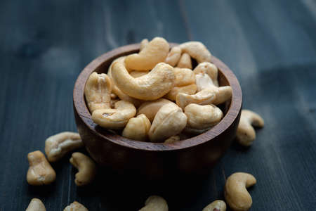 raw cashew nuts in wooden bowl on rustic table, healthy vegetarian snackの写真素材