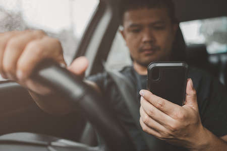 Asian man video calling via smart mobile phone inside a car, close up hand with phone. People lifestyle, social media communication concept.の写真素材