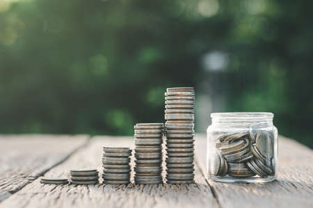 saving money and investment concept. Money coin stack growing graph and coins in jug glass. Balance...