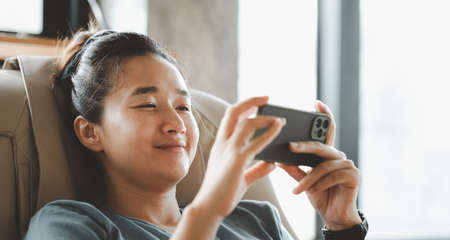 Closeup image of a young smart asian female holding and using smart phone. stay at home.